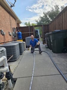 Homeowner and HVAC technician troubleshooting why the circuit breaker keeps tripping when AC kicks on by inspecting an electrical panel and air conditioning system.