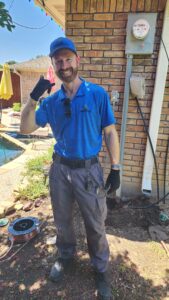 Professional electrician installing a whole-home surge protector before summer storms at a residential electrical panel to protect household electronics and appliances.