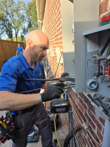 Licensed electrician inspecting an electrical panel in a Frisco home during summer.