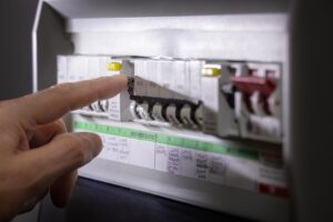 Electrician inspecting a circuit breaker panel in a Plano home during a summer heatwave.